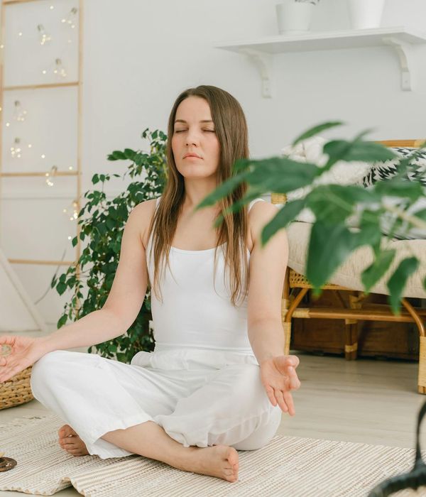Person sitting comfortably in a meditative pose in a cozy home environment.